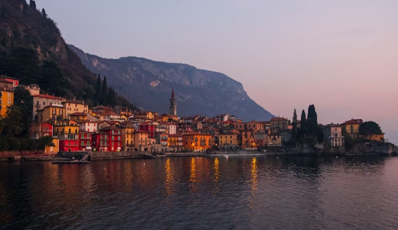 Colorful buildings of Varenna reflecting on Lake Como at sunset in Italy.
