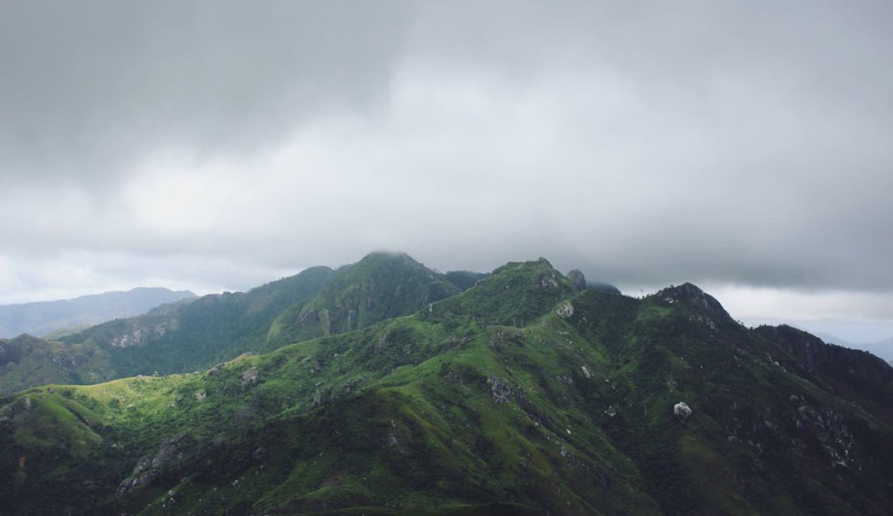 Mist rolls over lush green mountains, casting a moody, serene atmosphere.