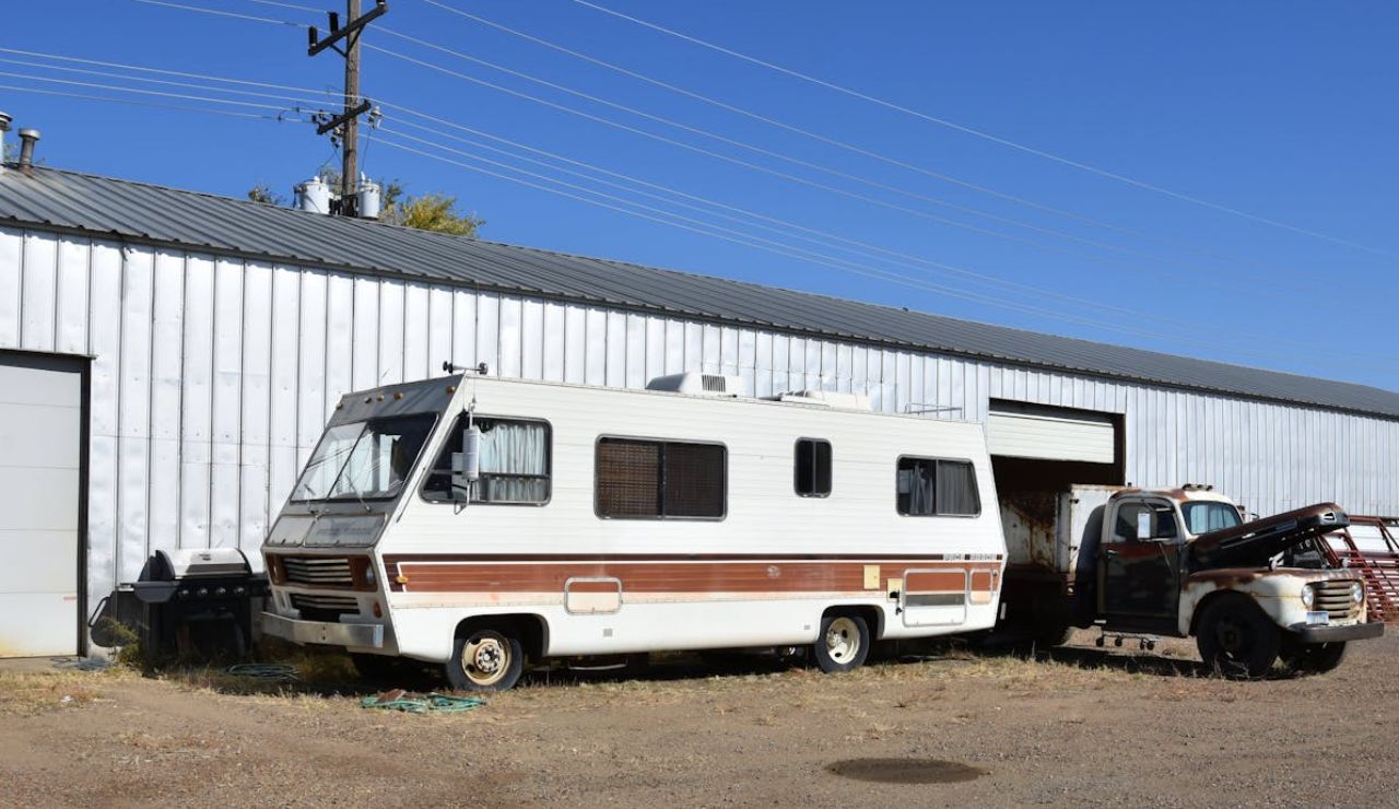  Older RV parked by a garage, showing the need for regular maintenance.