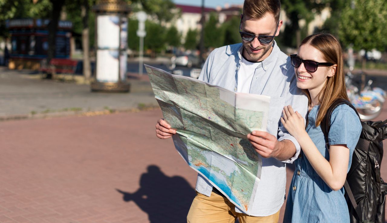A couple reviewing a paper map and pointing at nearby towns or neighborhoods.