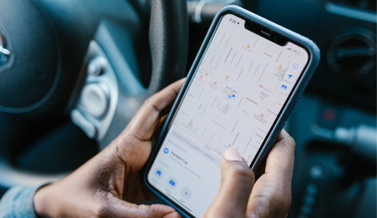 Person holding a smartphone with a map app open while sitting in a car.