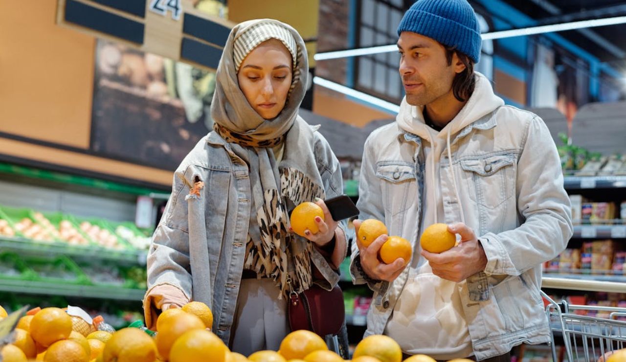 Couple selecting oranges in the produce section of a grocery store.
