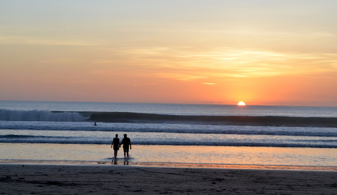 couple holding hands at sunset on a tropical beach in Maui
