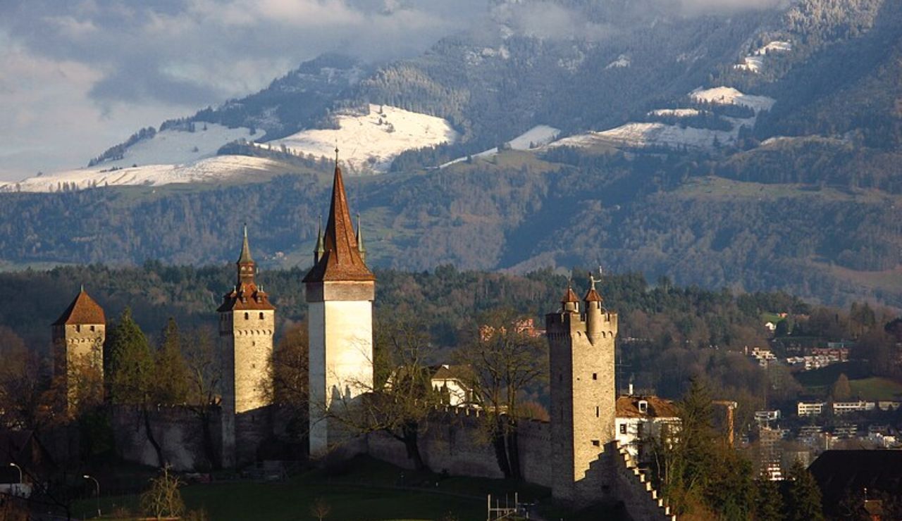 Medieval Musegg Wall and towers in Lucerne with snow-covered Alps in background.
