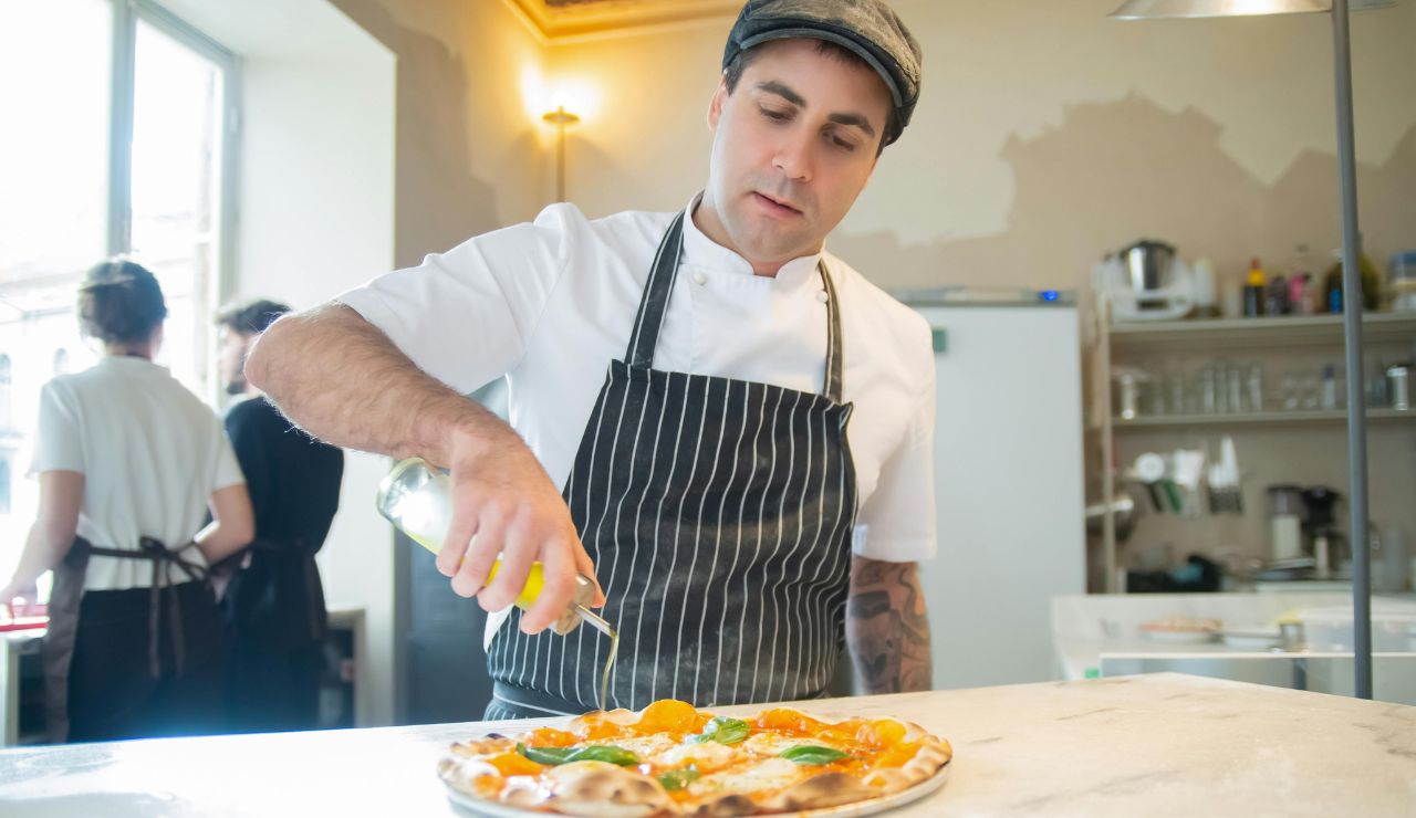 Neapolitan pizzaiolo pulling pizza from wood oven.
