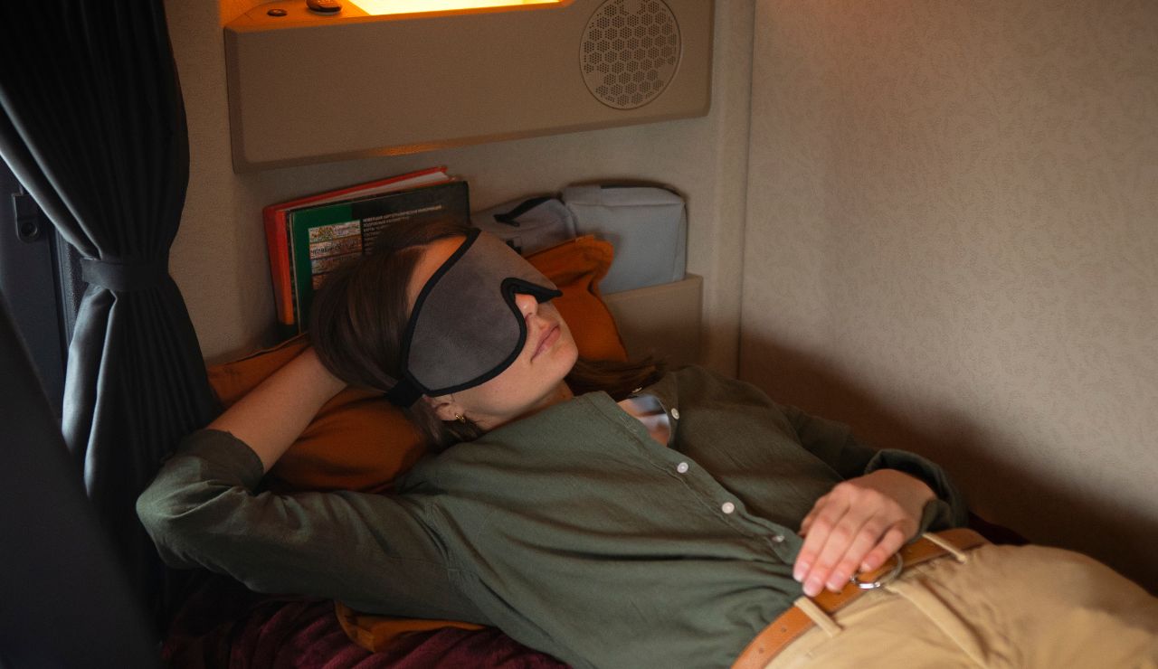 Airplane passenger using a sleep mask and neck pillow to rest during flight