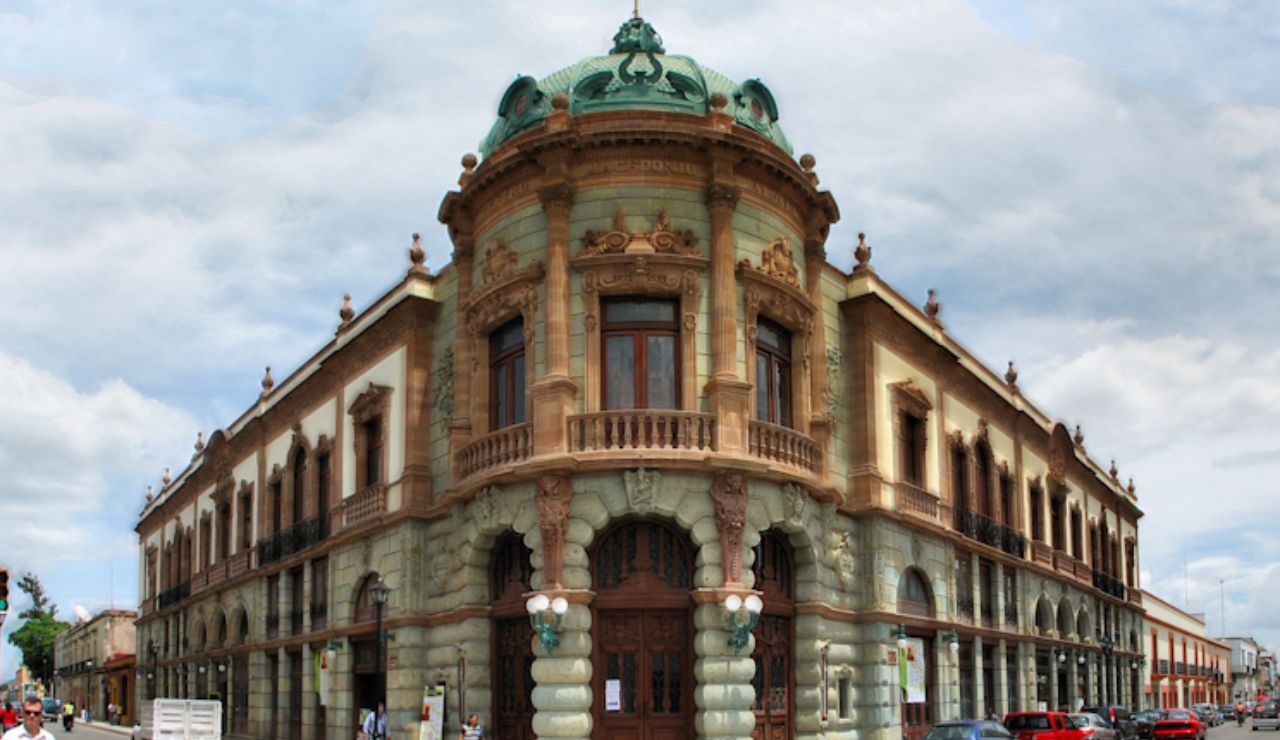 Ornate historic building with a green domed roof and classical architecture on a street corner in Oaxaca, Mexico.