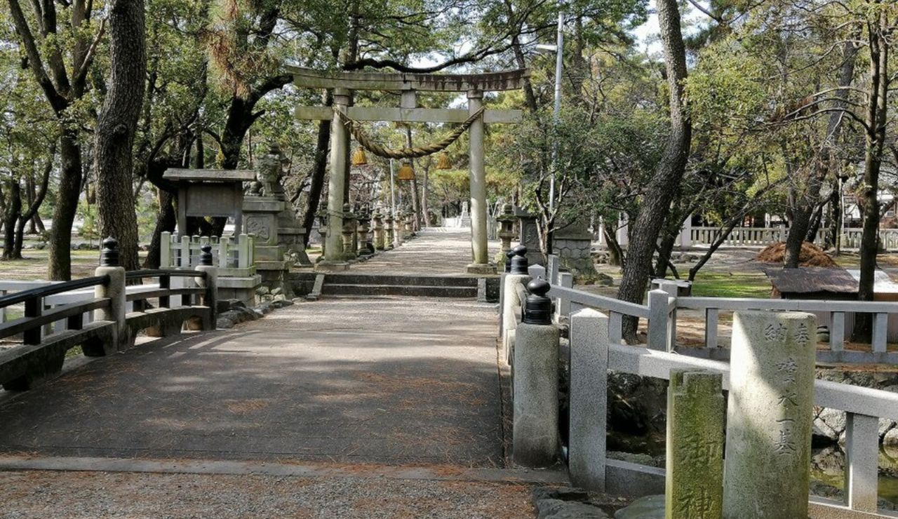 A peaceful path leading to a traditional Japanese torii gate, surrounded by trees and stone bridges in a serene garden.