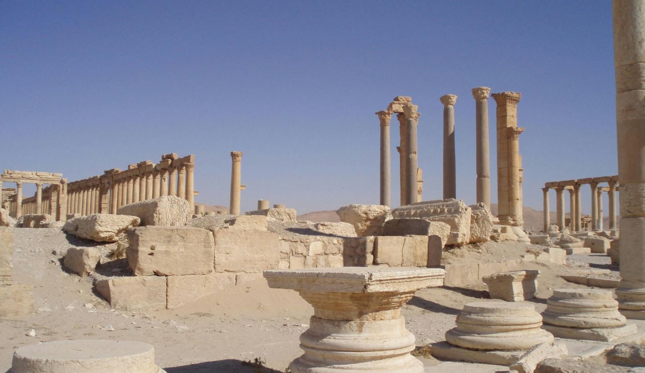 Ancient ruins of Palmyra in Syria, featuring tall stone columns and scattered remnants of classical architecture in a desert landscape.
