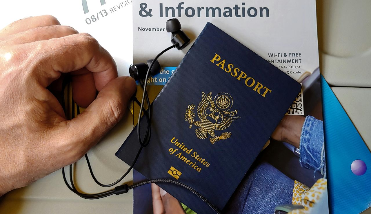 Hand holding a passport next to a laptop displaying visa application info