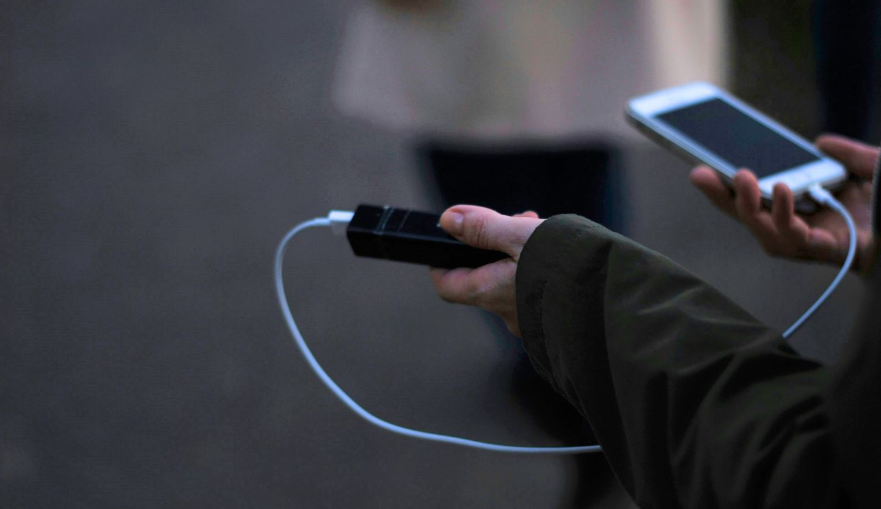 Person using a portable charger on their phone during a night walk