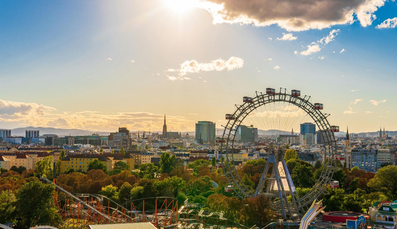 Scenic view of Vienna’s Prater amusement park at sunset, featuring the iconic Wiener Riesenrad Ferris wheel with the city skyline in the background.