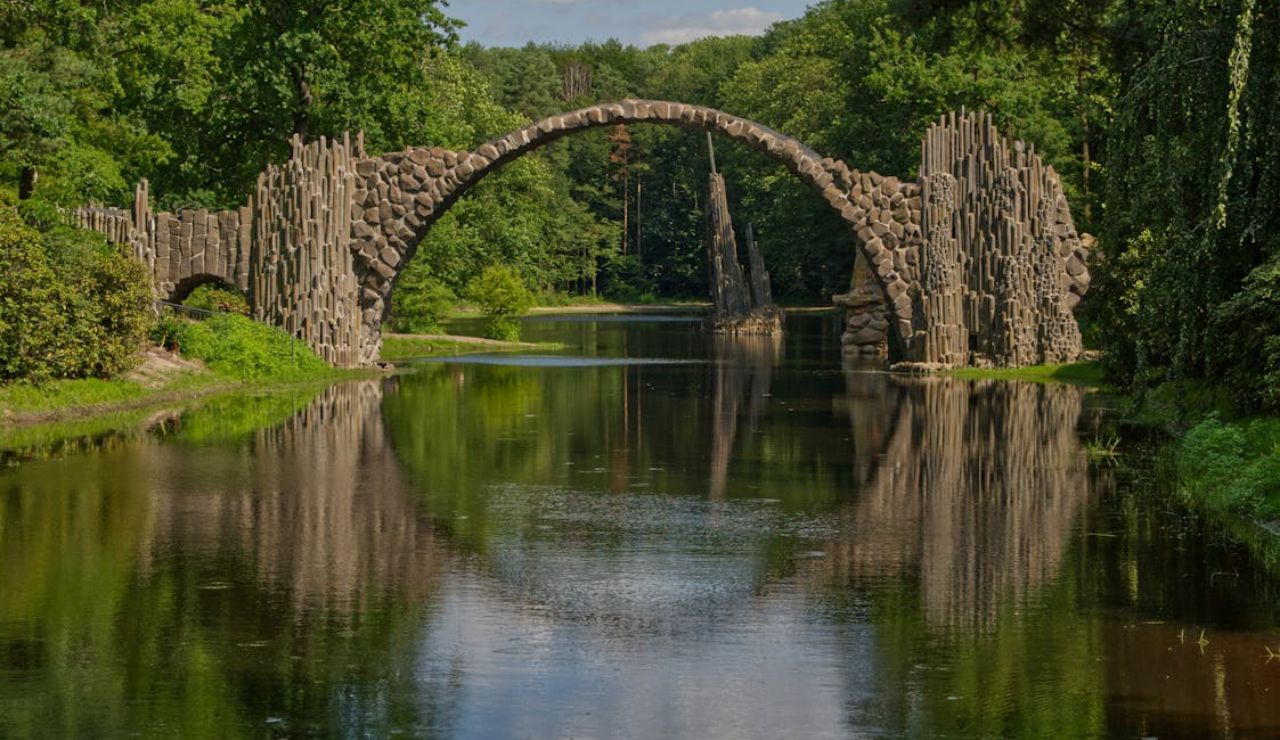 Stone arch of Rakotzbrücke (Devil’s Bridge) in Germany reflected perfectly in a calm forest lake.
