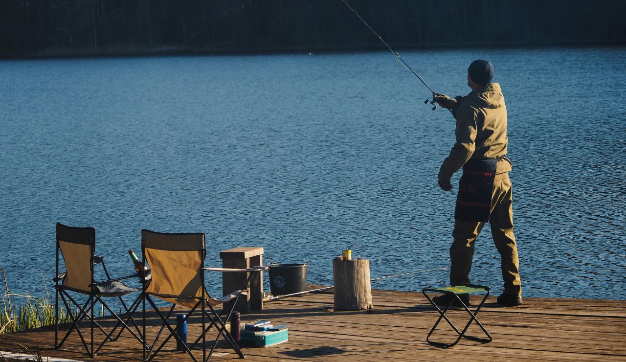 Angler casting a line in a calm lake surrounded by forest