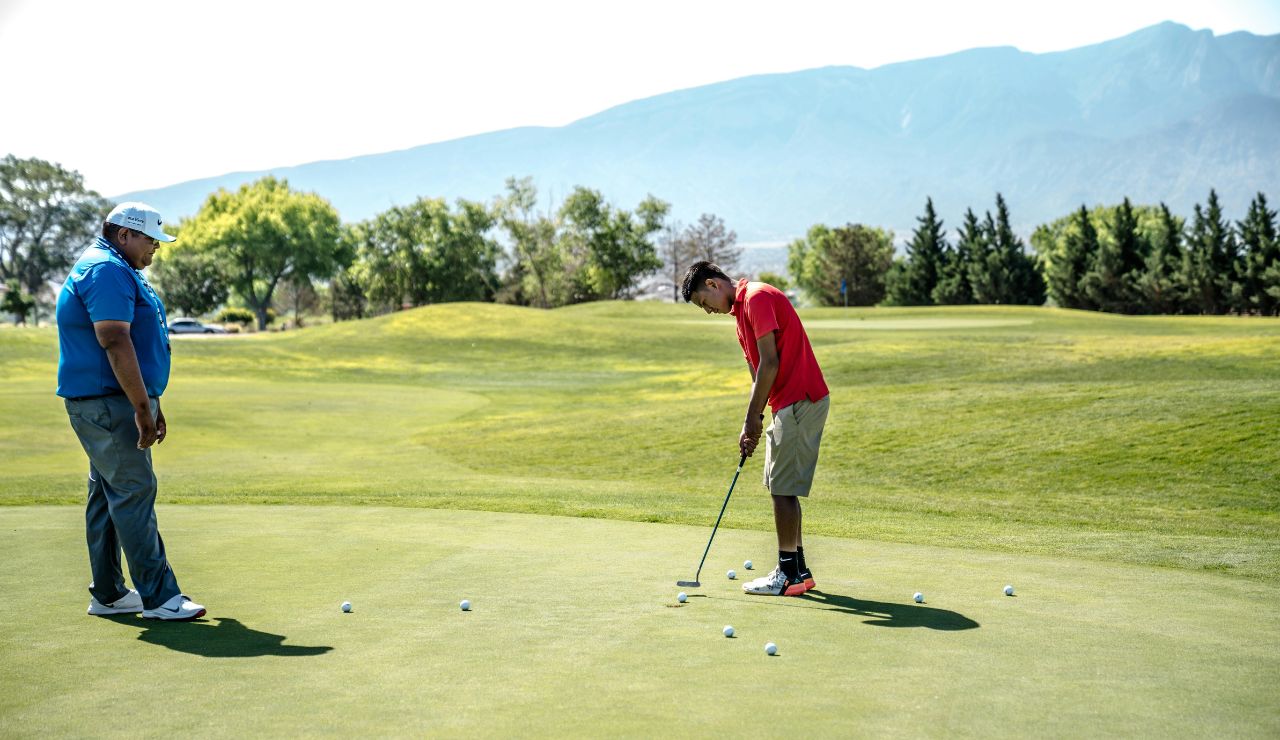 Golf course with fairways framed by trees and distant mountains