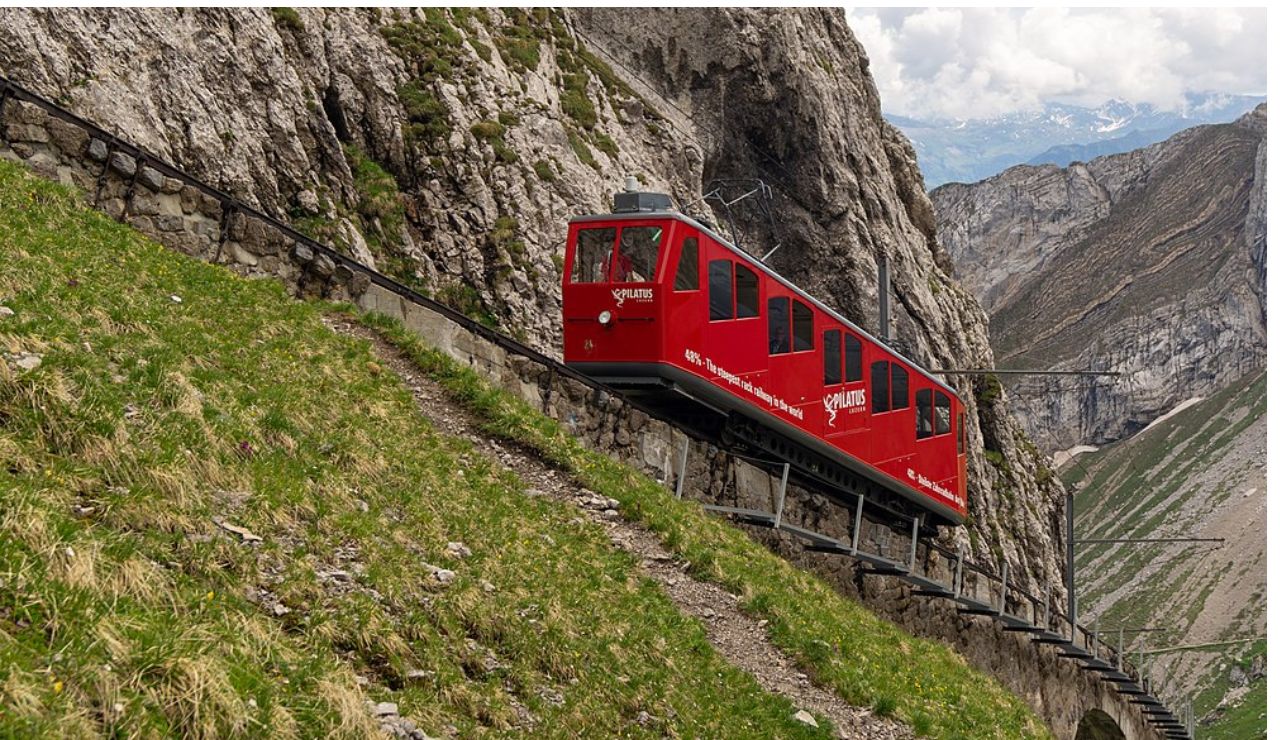 Bright red cogwheel train climbing the steep slope of Mount Pilatus in Switzerland.