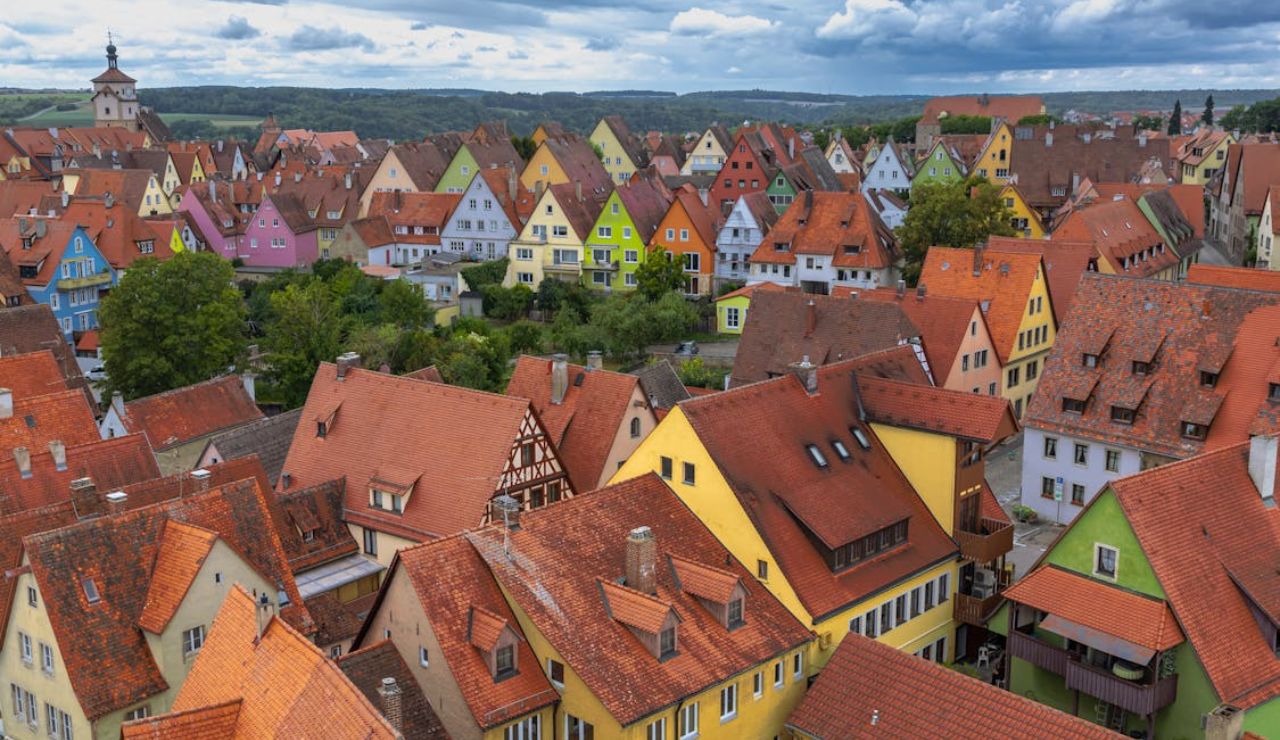Colorful traditional houses with red-tiled roofs in a quaint German village under a cloudy sky.