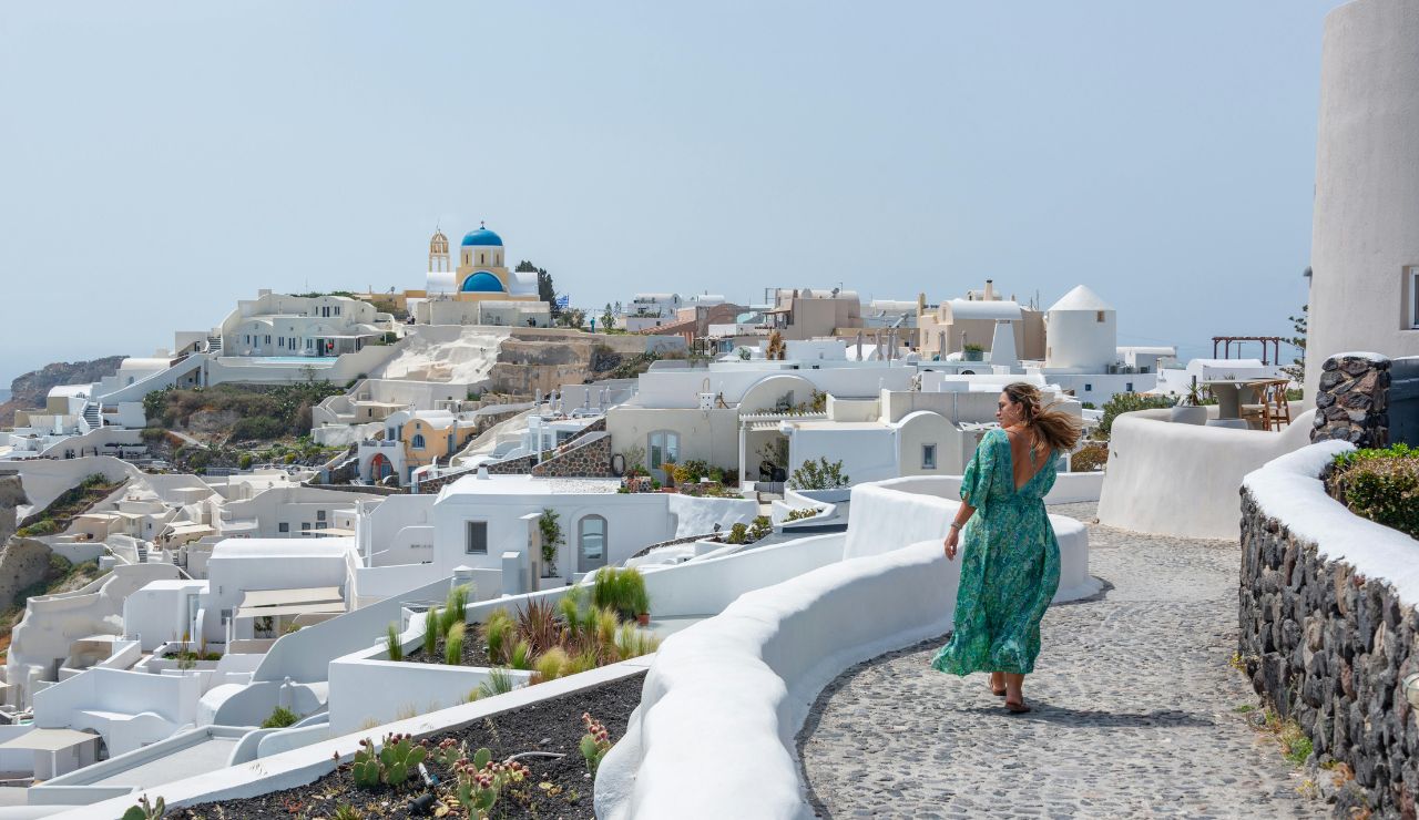 Woman walking along a white-washed path in Santorini, Greece.