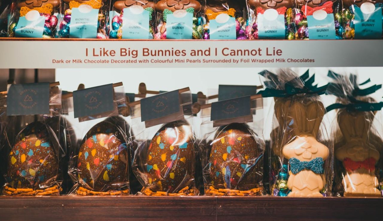 Display of Easter-themed Belgian chocolates, including large decorated chocolate eggs and playful chocolate bunnies, with a humorous sign reading “I Like Big Bunnies and I Cannot Lie.”