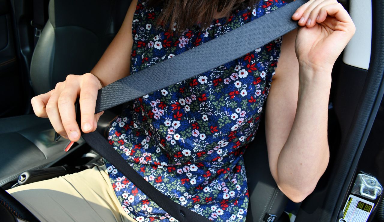 Person fastening a seatbelt while sitting in a car.