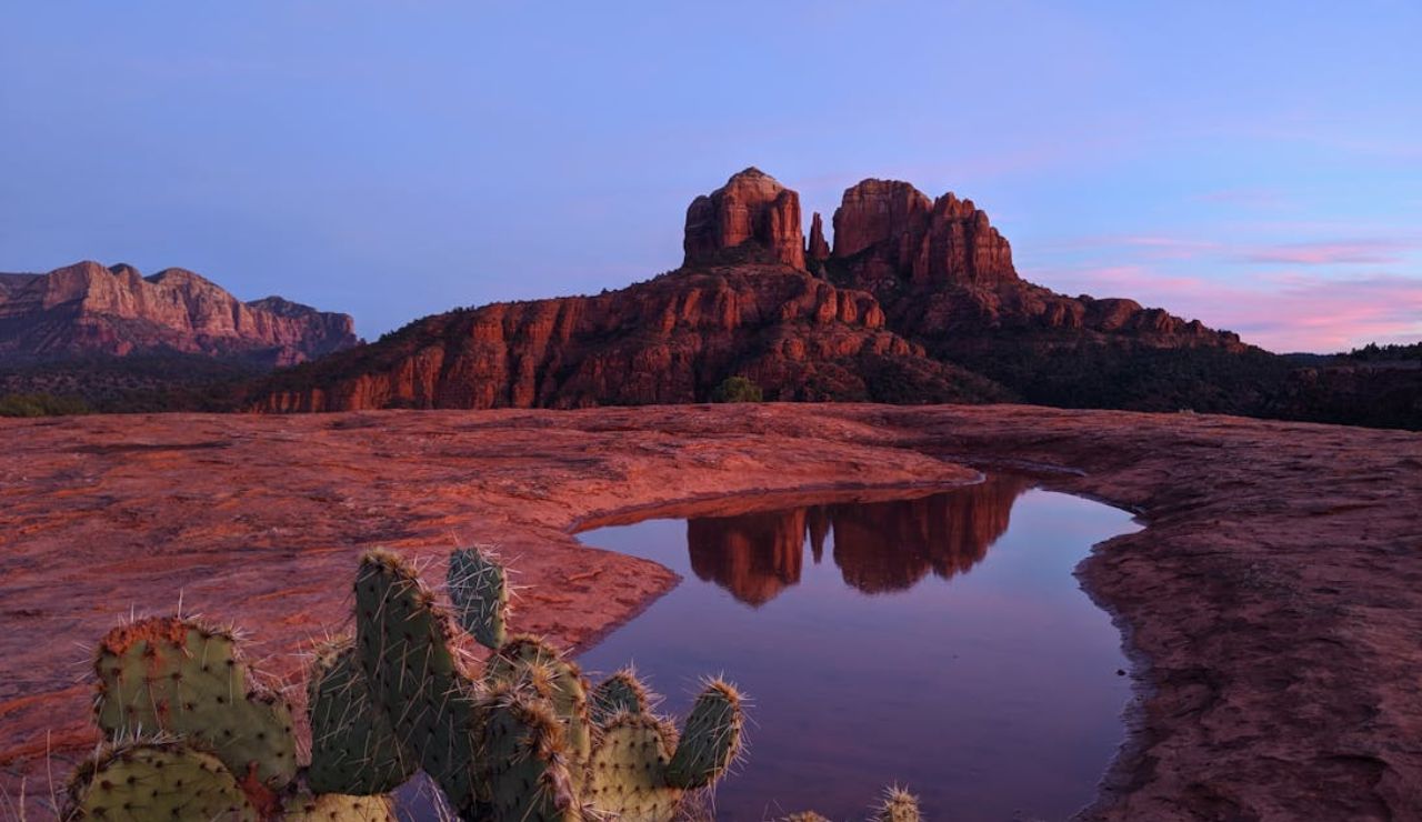 Red rock formations reflected in a water pool at sunset in Sedona, Arizona.