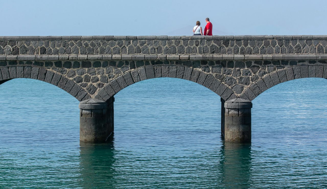 Couple walking on Old Seven Mile Bridge above clear blue water