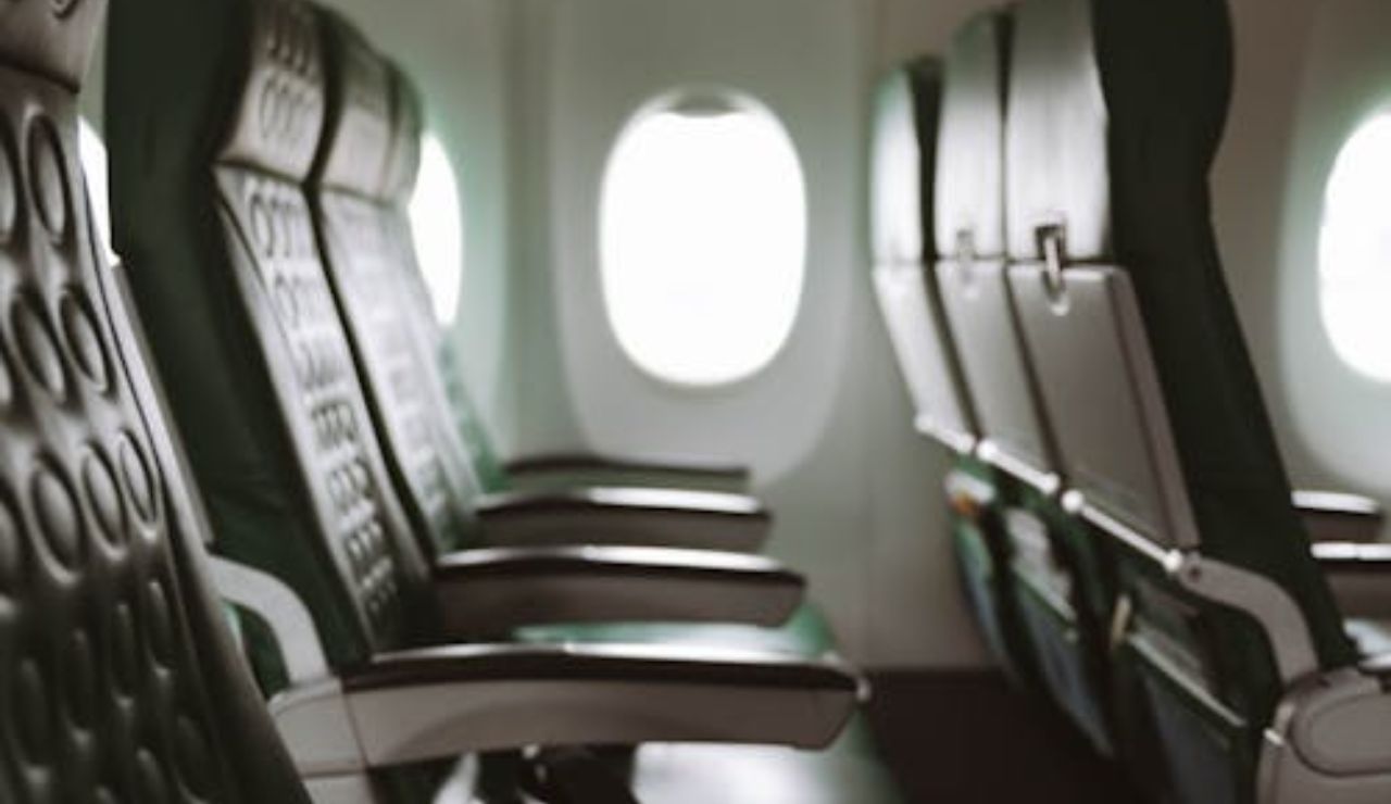 Side view of empty airplane seats by the window, with seatbelt straps visible.