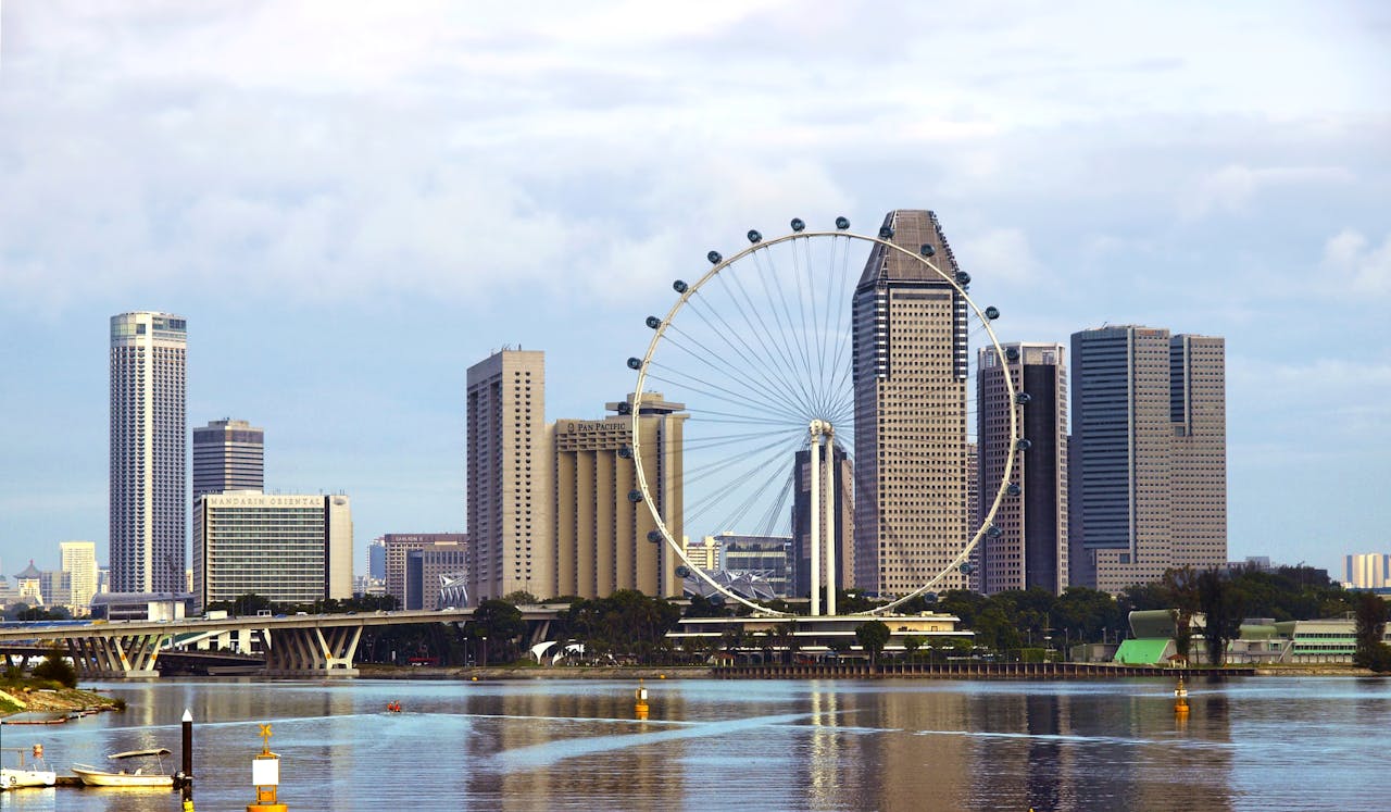 ChatGPT said:
Daytime cityscape featuring a large Ferris wheel (Singapore Flyer) set against modern skyscrapers, with reflections shimmering on the water below.