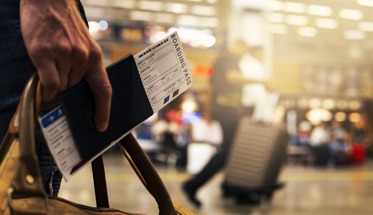 Slim passport wallet holding passport, credit card, and boarding pass at airport counter.