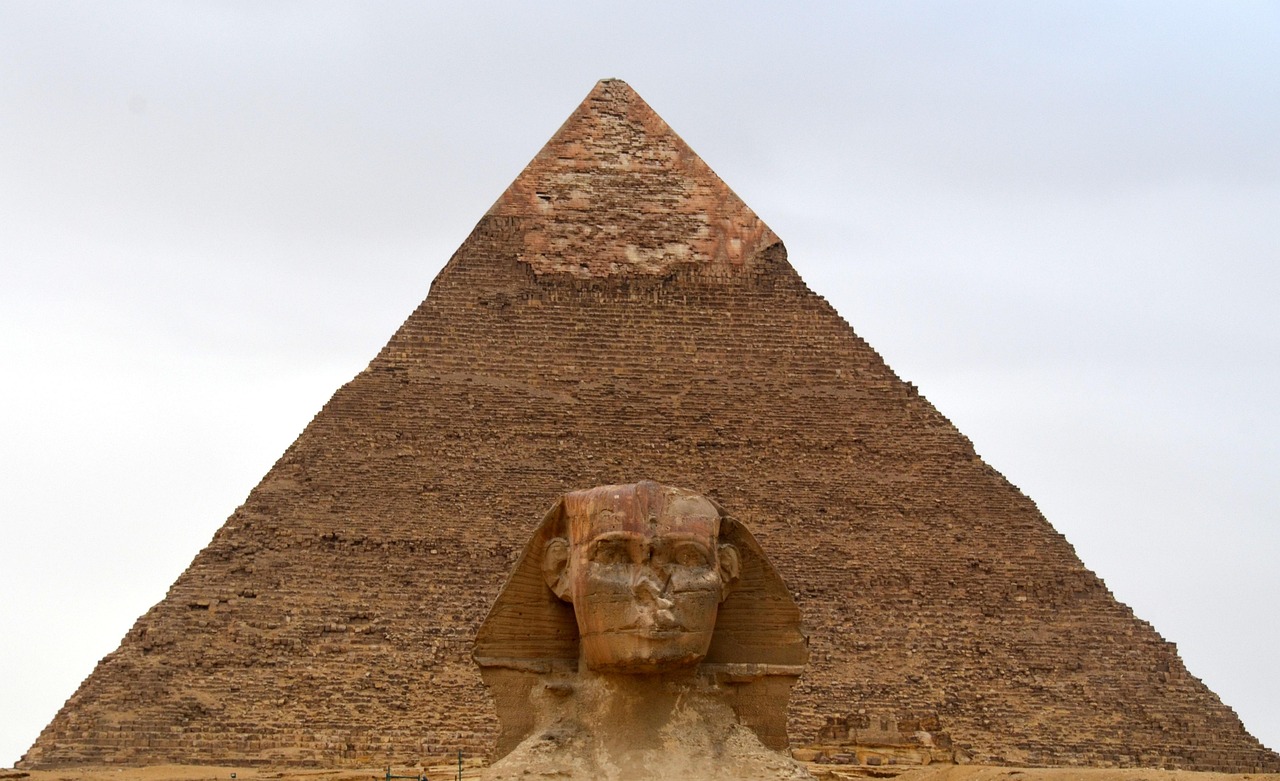 The Great Sphinx of Giza stands before the Pyramid of Khafre beneath a cloudy sky.