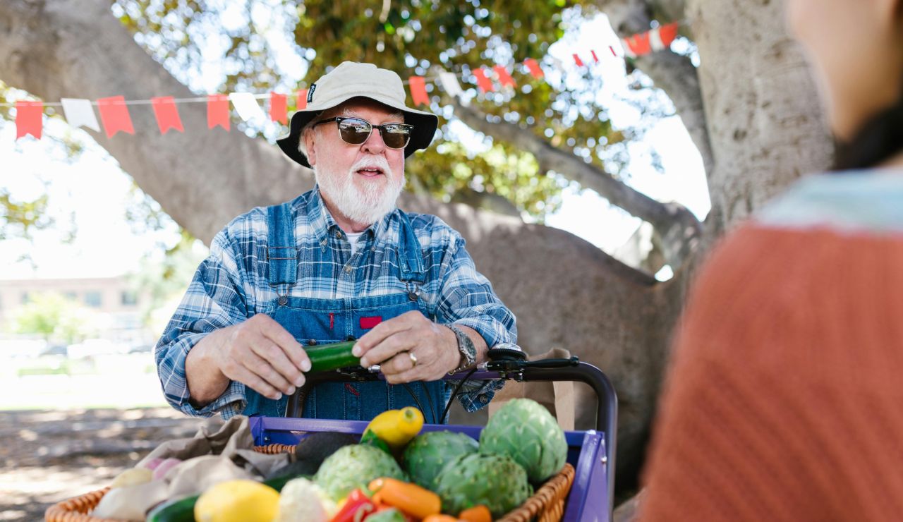A traveler chatting with a smiling local vendor at an outdoor market stall.