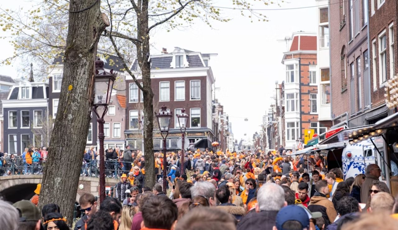 Dense crowd filling a street in Amsterdam during an event, illustrating the city's over-tourism concerns.
