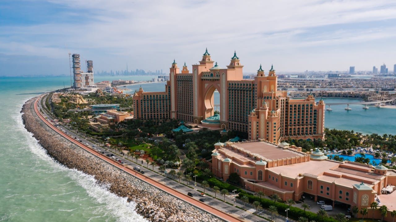 Aerial view of Atlantis The Palm resort on Palm Jumeirah island in Dubai, surrounded by water and city skyline in the background.