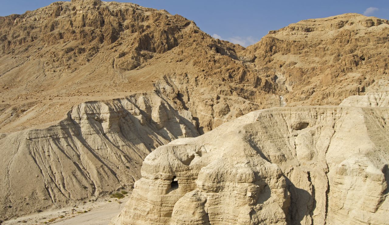 Rocky desert cliffs and caves in Qumran, Israel, known for the discovery of the Dead Sea Scrolls.