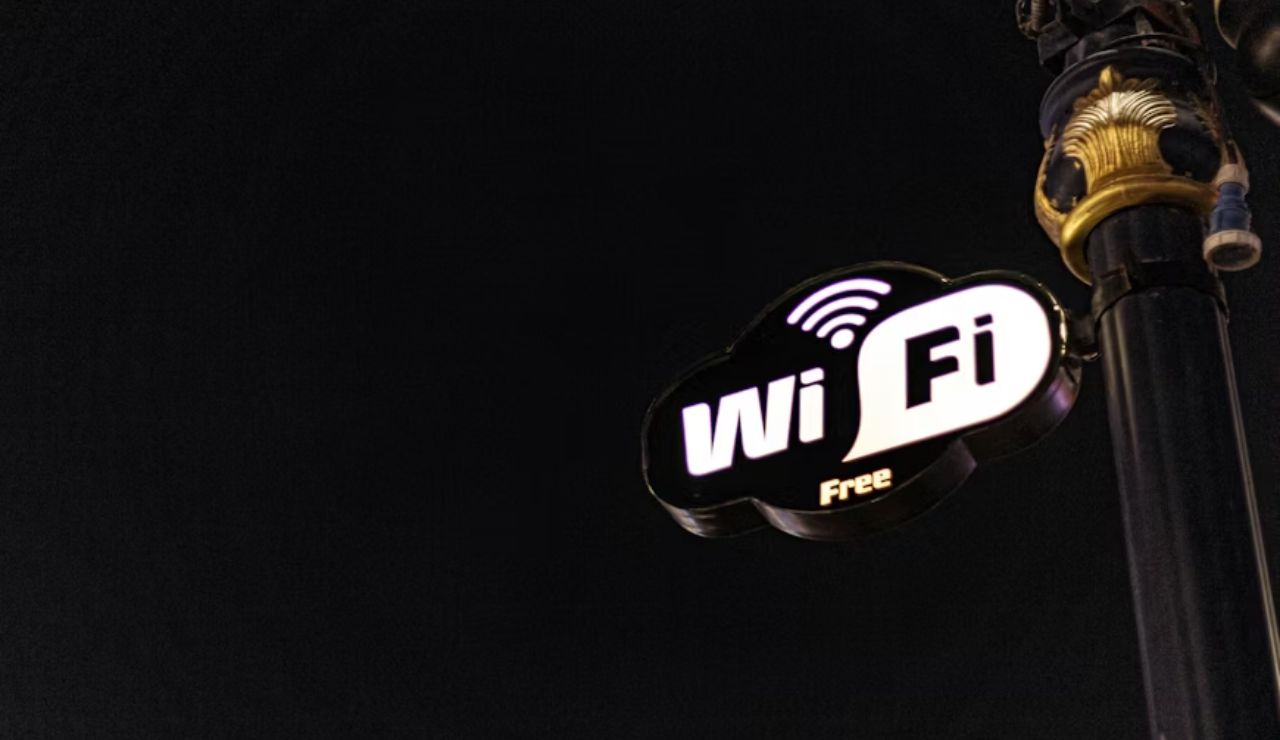 Illuminated "Free WiFi" sign attached to a decorative street pole against a dark night sky.