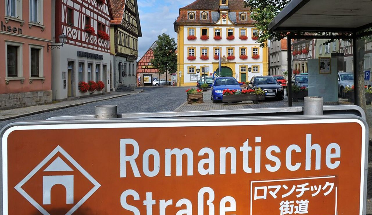 Street view of a charming German town with half-timbered buildings and a sign reading “Romantische Straße” in German and Japanese.