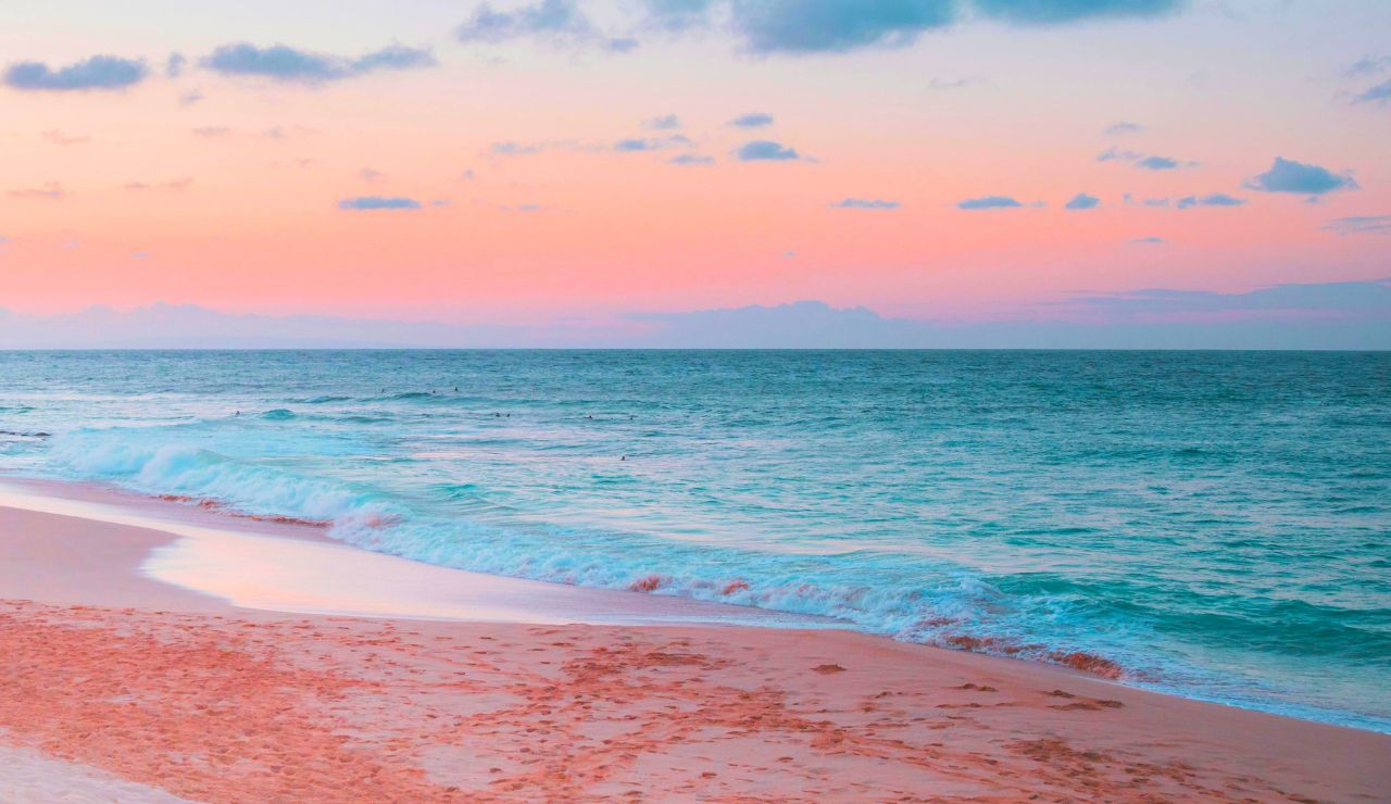 A blush-pink sand beach encircling a vibrant lagoon in Tikehau.