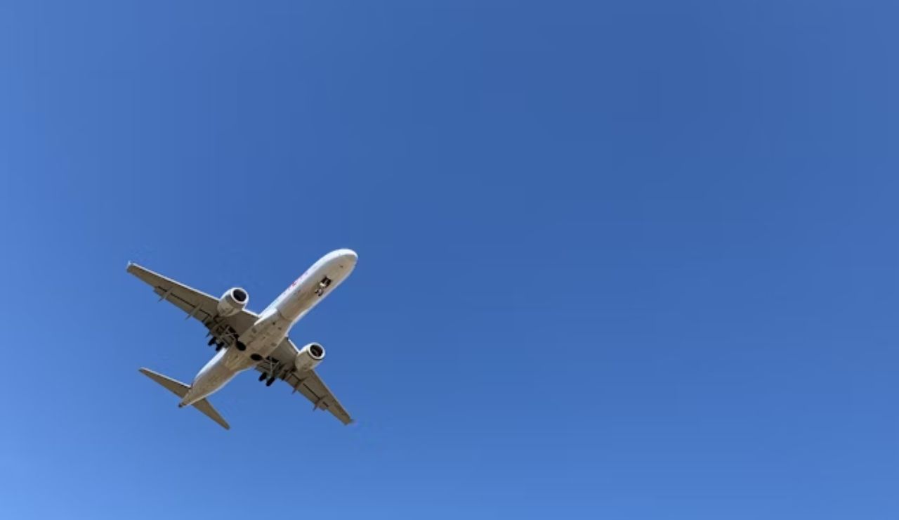 Airplane flying overhead against a clear blue sky.