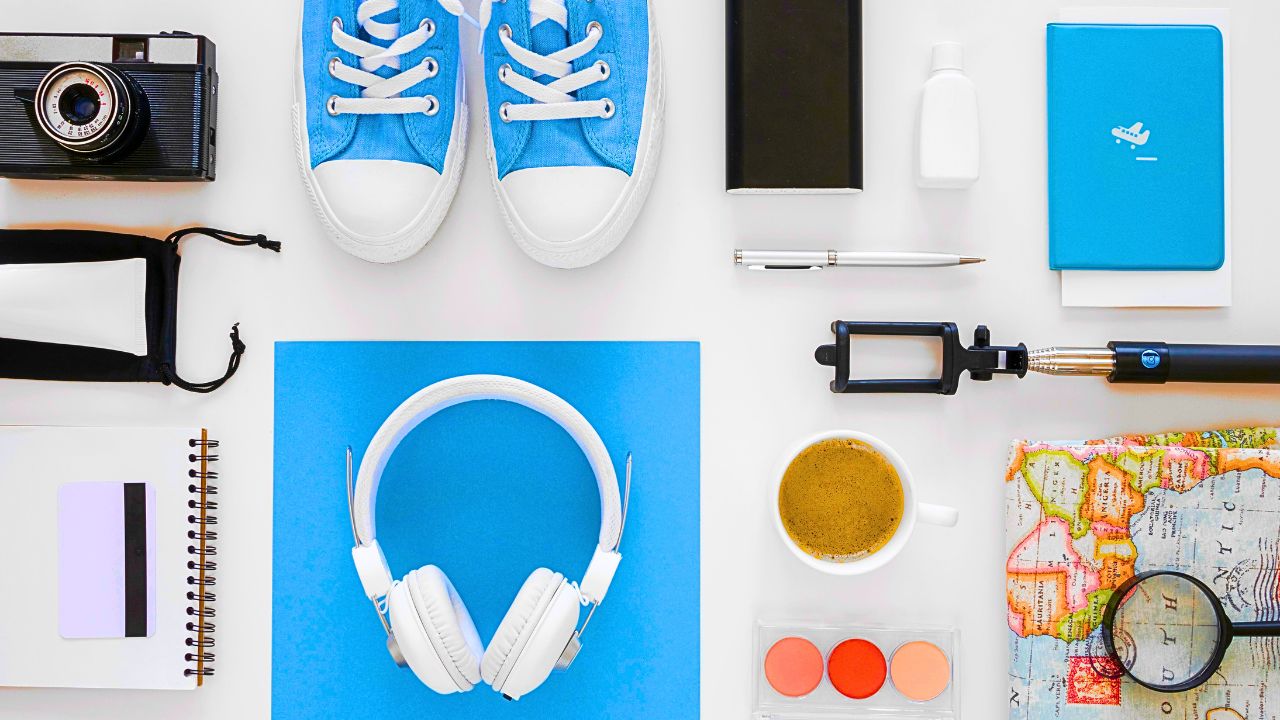 Flat lay of essential travel accessories including headphones, water bottle, and passport wallet.