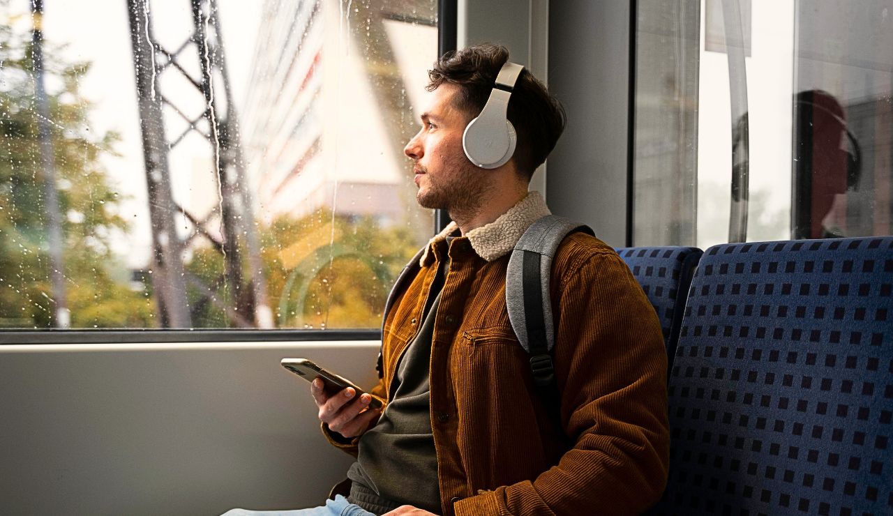 Passenger wearing noise‑canceling headphones, sitting by an bus window.