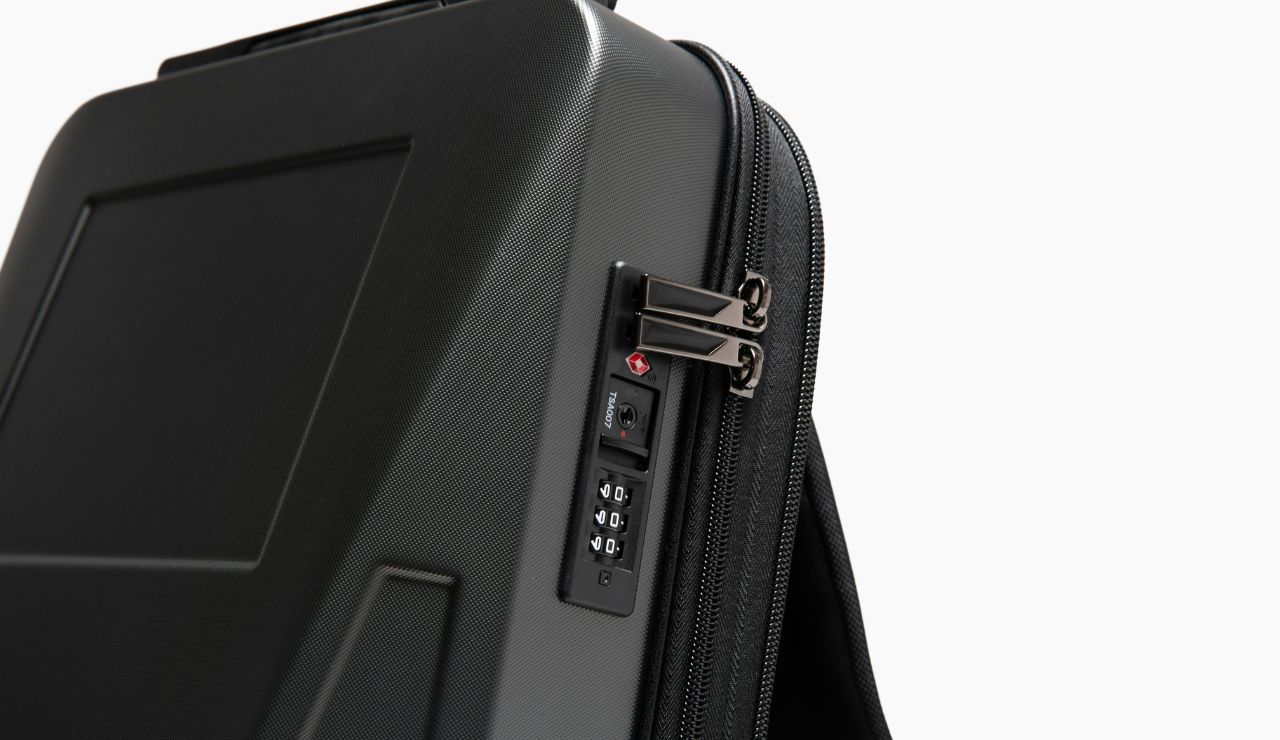 Traveler securing a suitcase with a small TSA‑approved lock at the airport.