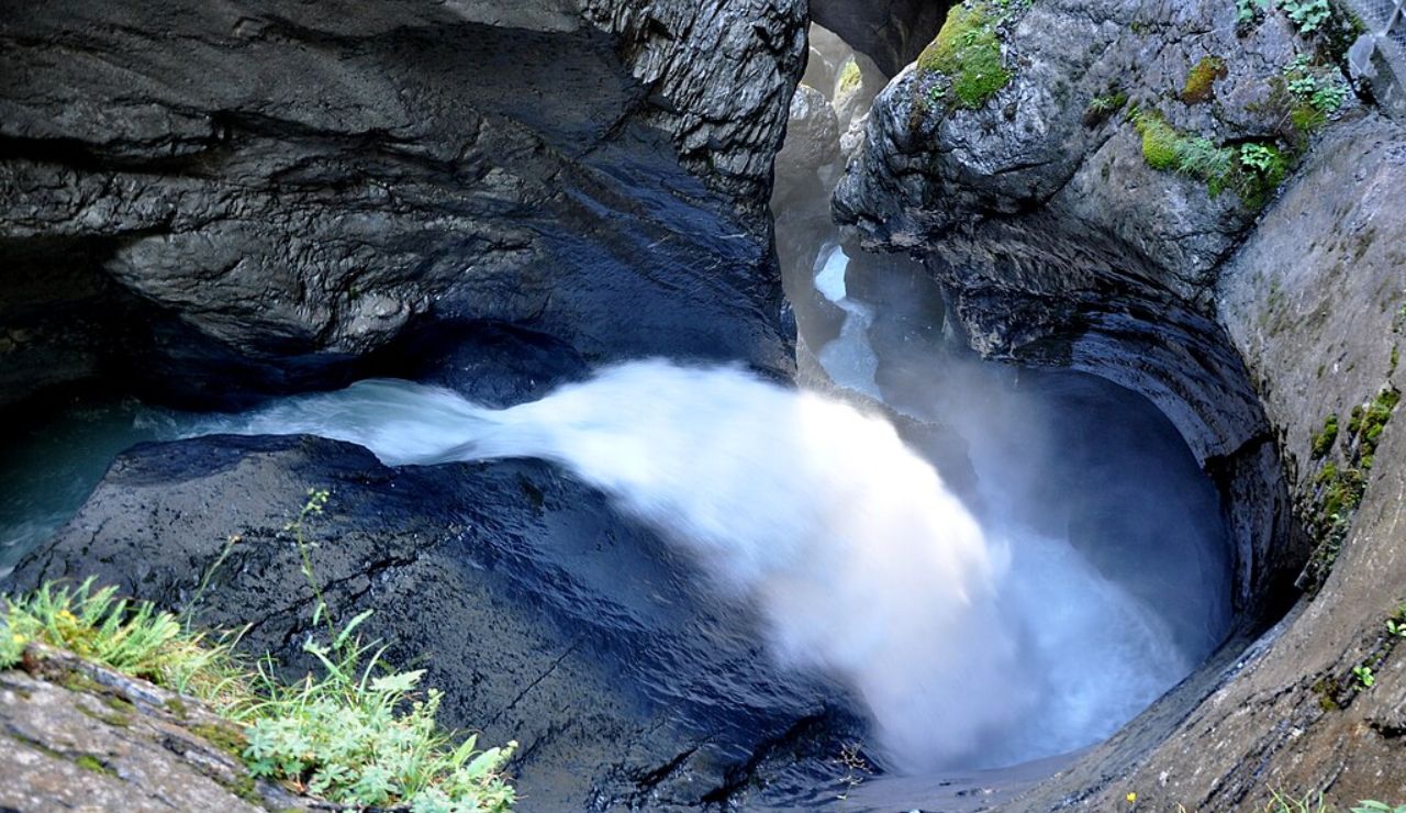 A powerful waterfall rushing through a narrow, rocky gorge with mist rising from the churning water.