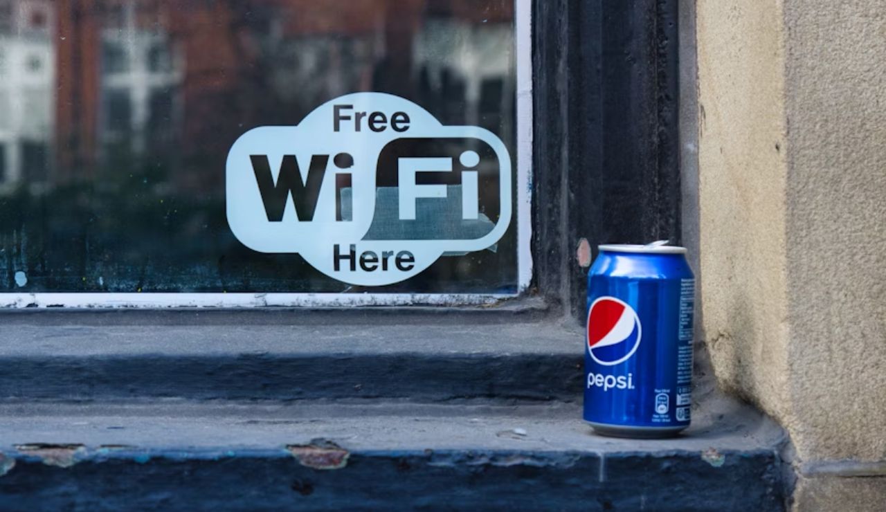 A can of Pepsi placed on a windowsill next to a sign that says "Free WiFi Here" on a glass window.