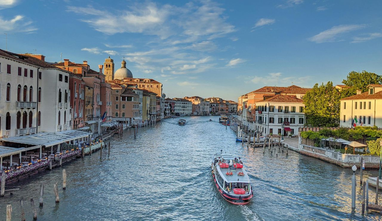 Gondola moving along Venice’s Grand Canal under a stone bridge.
