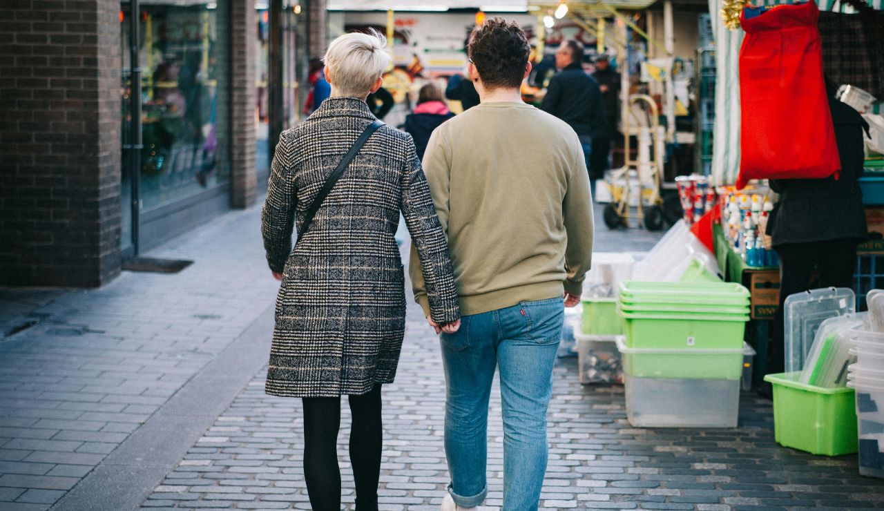 A couple exploring on foot down a quiet cobblestone street lined with shops.