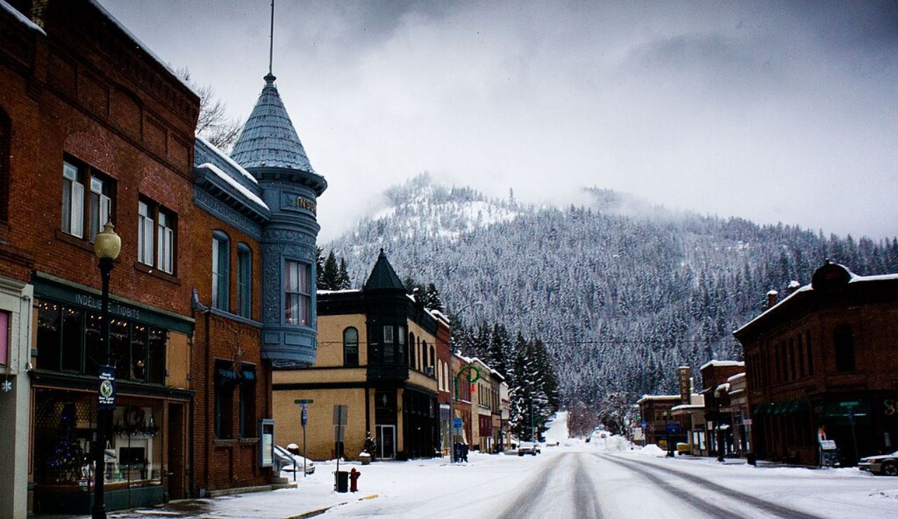 Snowy mountain town with historic brick buildings and misty pine hills.