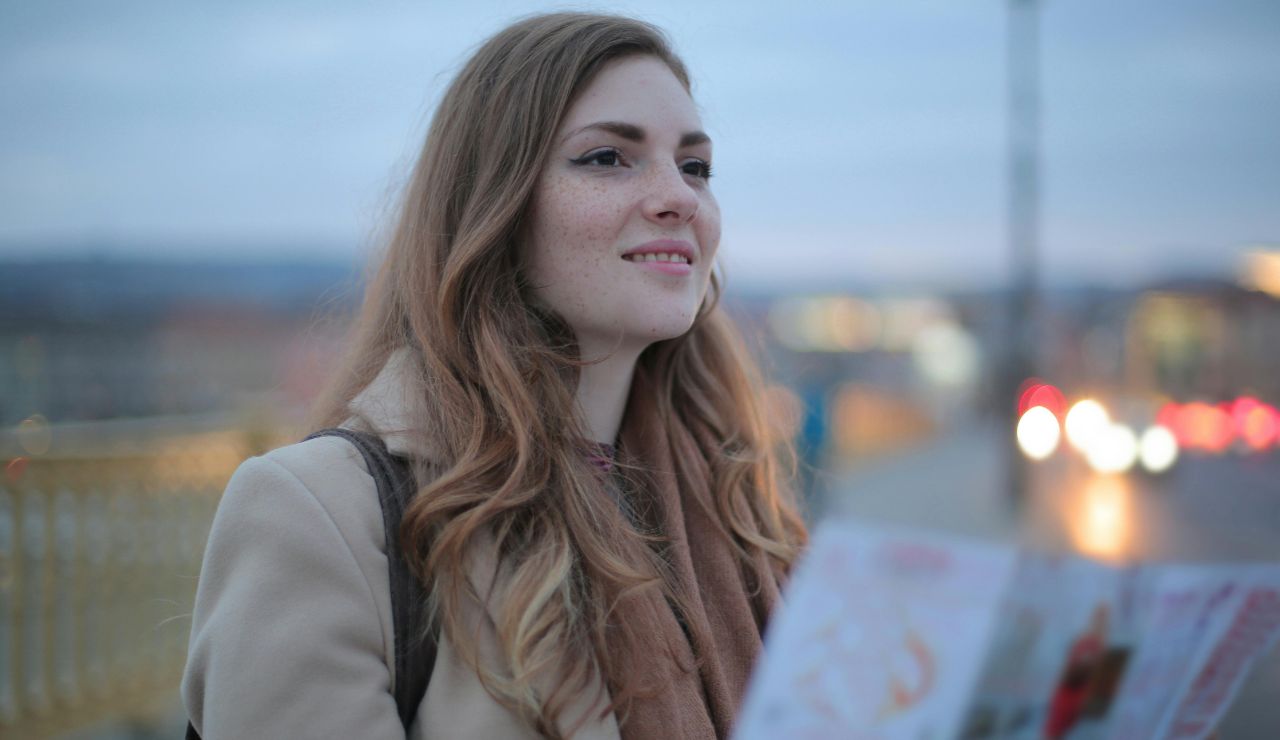 A solo traveler smiling while navigating through winding, unfamiliar alleyways.