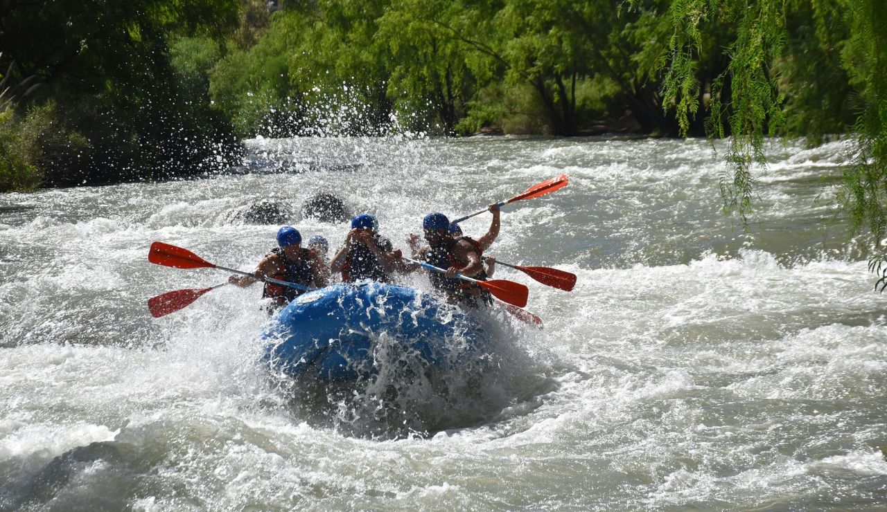 Group of people rafting through a river canyon with whitewater rapids