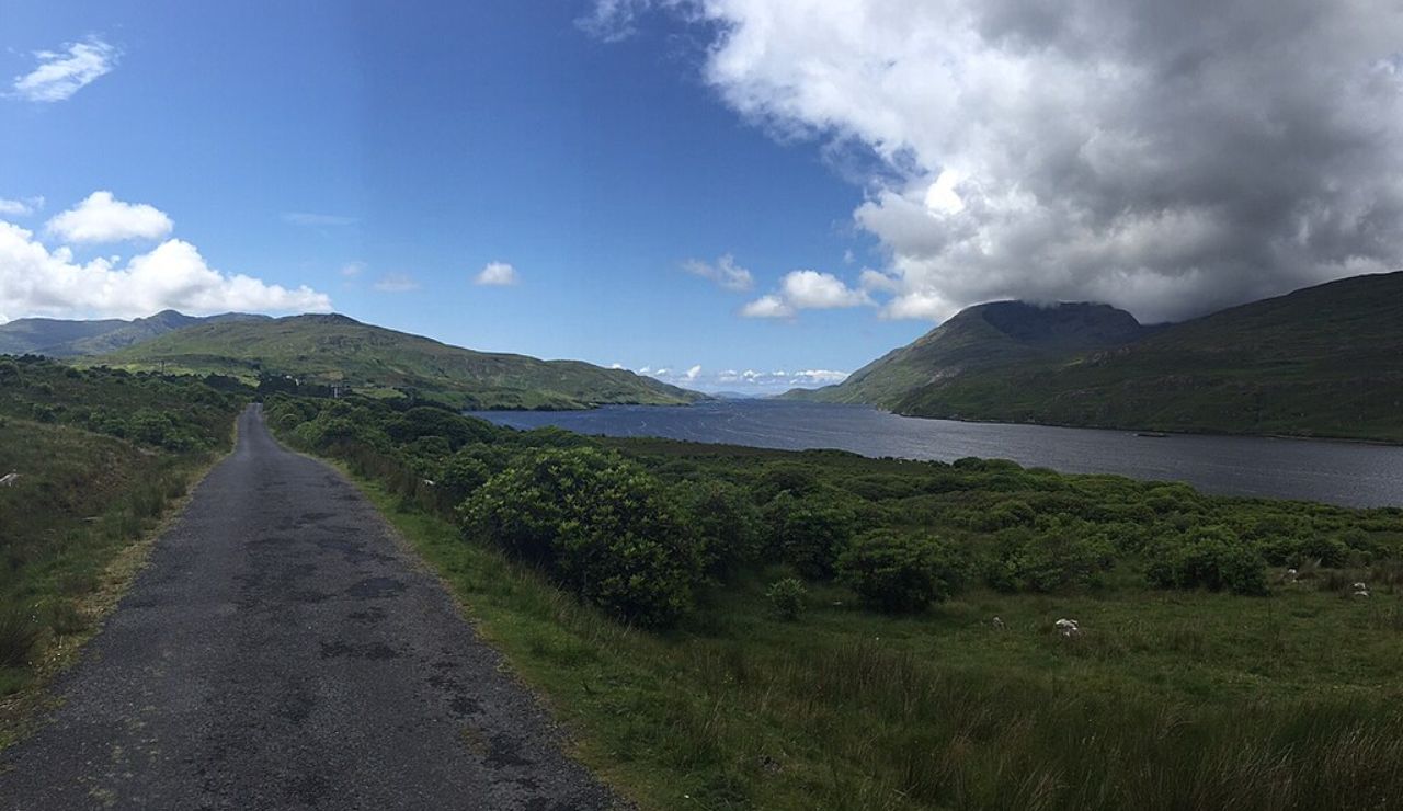 Narrow road along the Wild Atlantic Way in Ireland with coastal views and green hills.