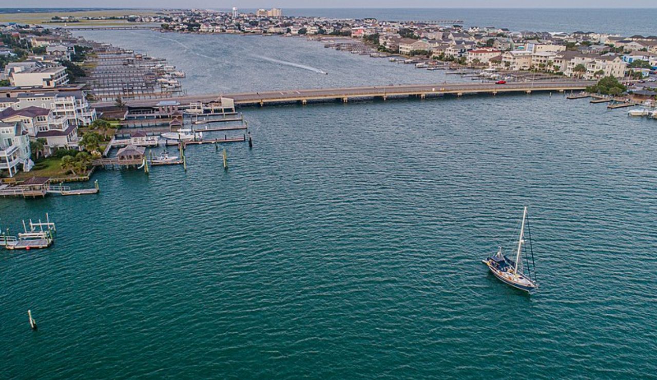 Aerial view of Wrightsville Beach, North Carolina, with houses, docks, and a sailboat on the water.